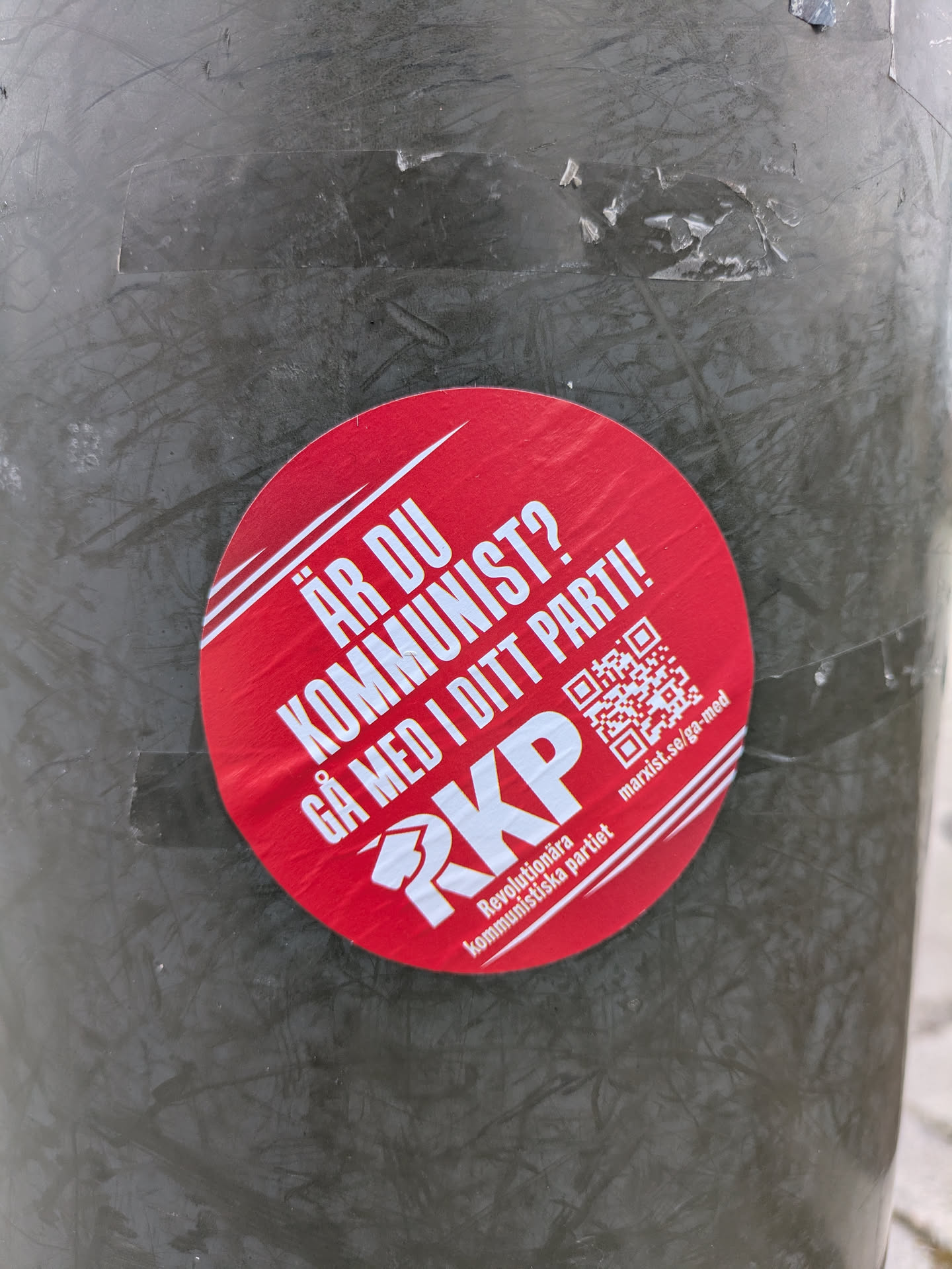 A red round sticker promoting the Revolutionary Communist Party (RKP) in Sweden. The sticker contains a QR code linking to marxist.se/ga-med, and includes the party's logo and name.
