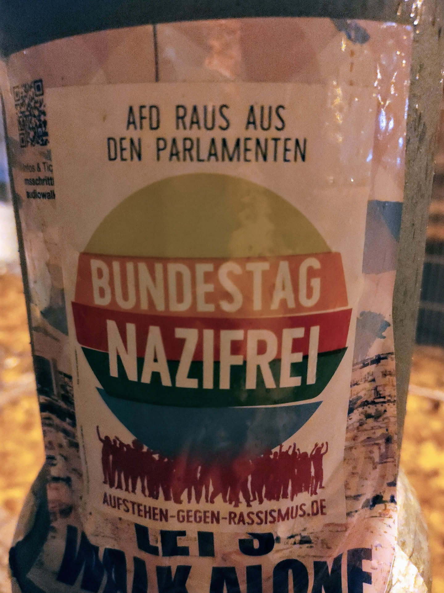 Sticker promoting the removal of the AfD (Alternative for Germany) from parliament and advocating for a Nazi-free Bundestag.  Features a QR code linking to aufstehen-gegen-rassismus.de.  The sticker also includes an image of many people raising their fists in solidarity.