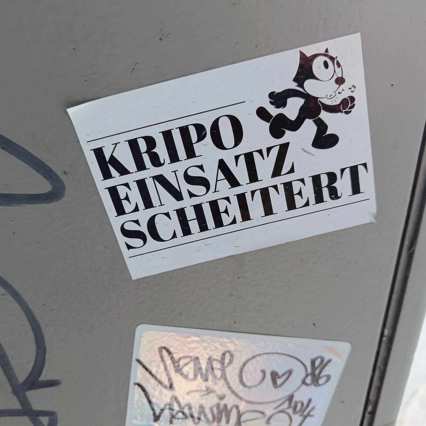 A sticker featuring Felix the Cat with the text "Kripo Einsatz Scheitert" (Criminal Police Operation Failed) in German. The sticker has a minimalist design with bold text and a simple illustration.