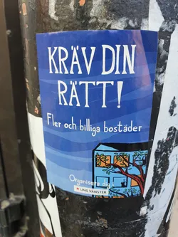A blue sticker with white text that says "KRÄV DIN RÄTT!" which translates to "Demand your right!" in Swedish. Below it, it says "More and affordable housing" in Swedish. At the bottom there is an illustration of a building with a tree and the text "Organize yourself with Ung Vänster."