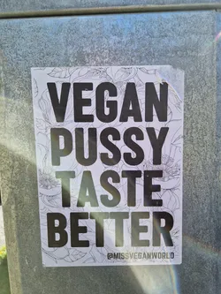 A sticker with a bold text message on a floral background. The text reads 'Vegan Pussy Taste Better' and includes a social media handle at the bottom.
