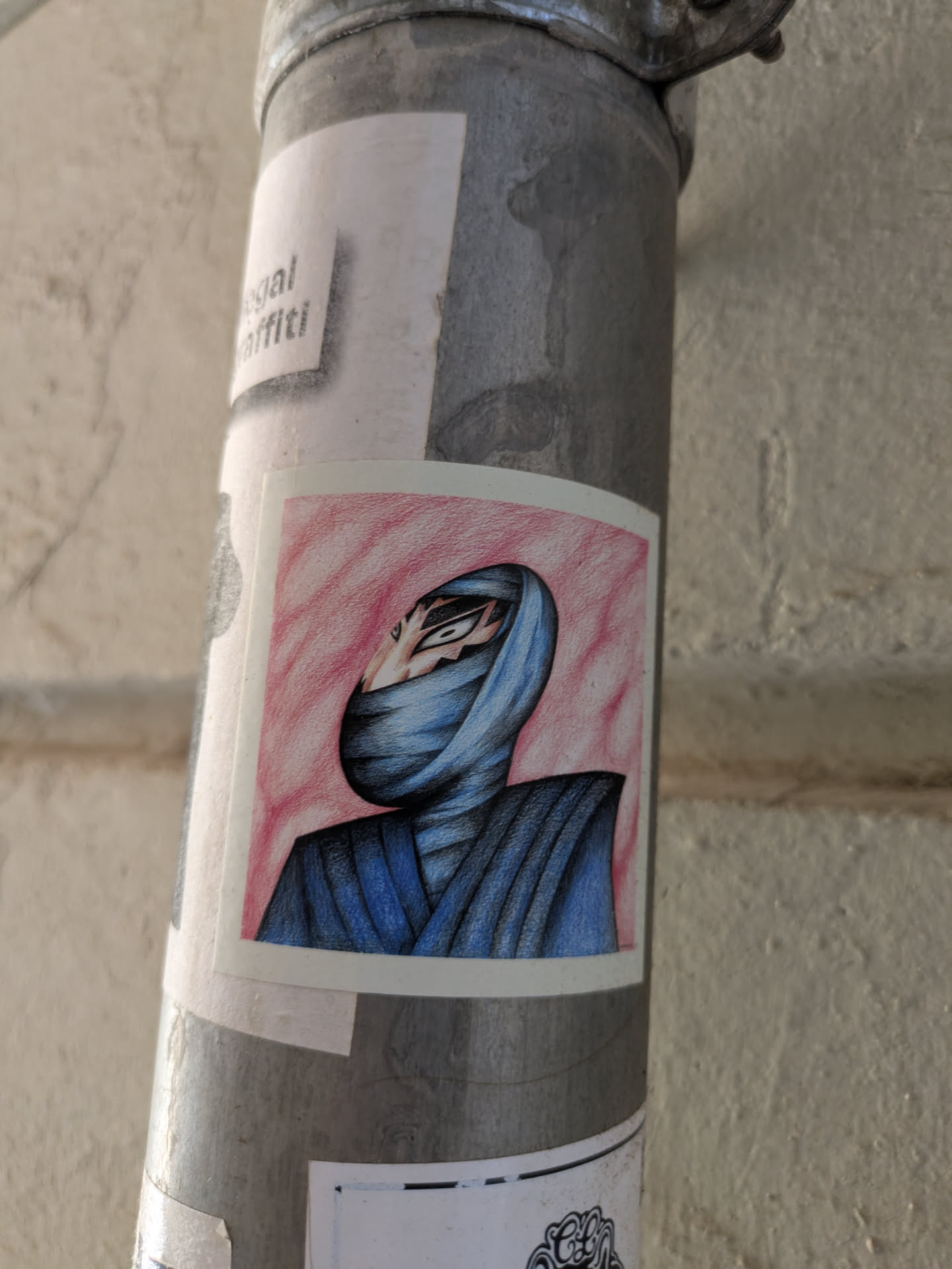 A sticker features a character wrapped in blue clothing against a pink background. The character's eyes are visible through an opening in the clothing, and their face is partially concealed.