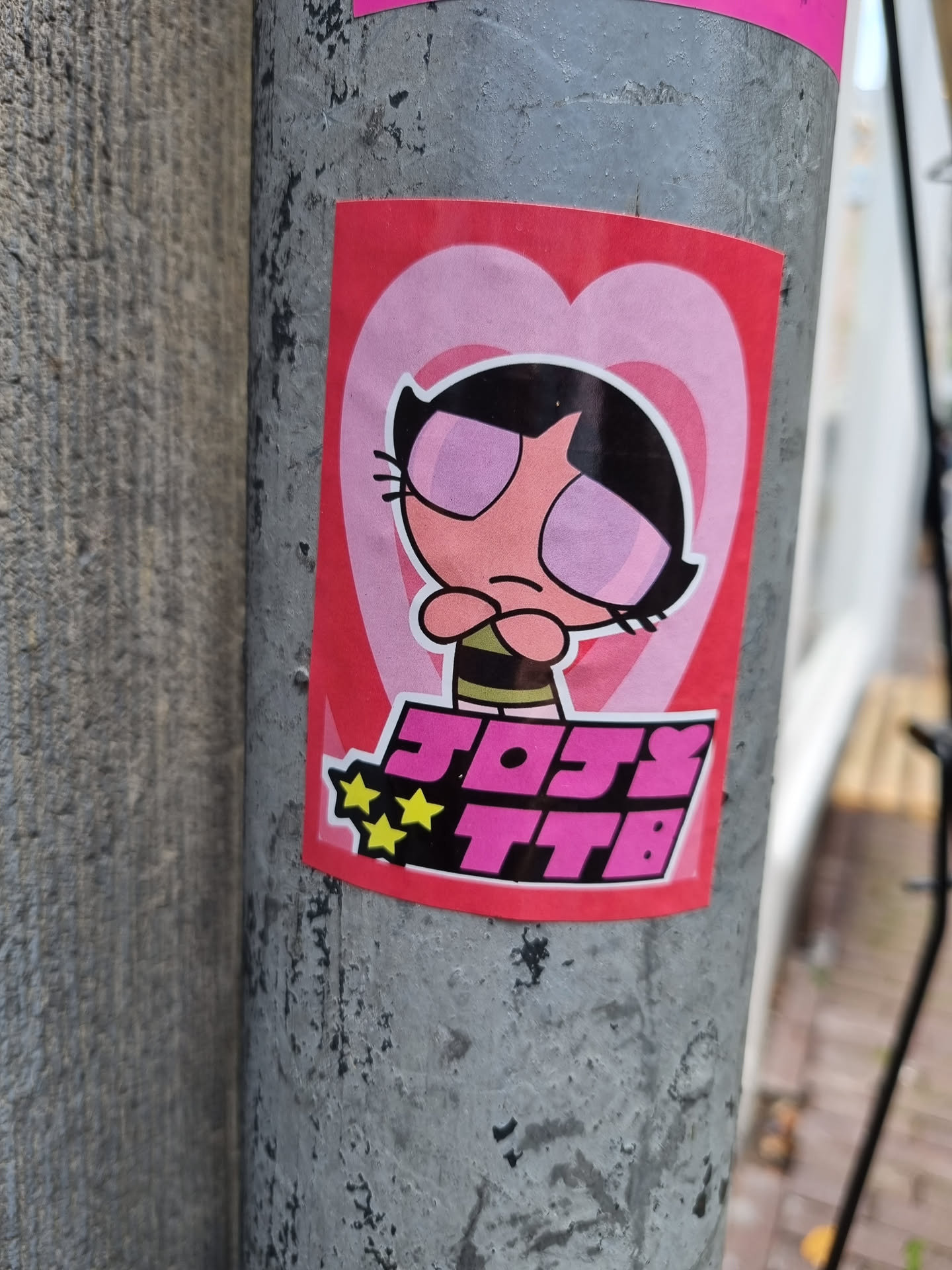 A pink and red sticker featuring a character resembling Buttercup from the Powerpuff Girls, with the text "JOSY TTB" and two stars underneath.  The character has pink eyes and is shown with a slightly grumpy expression. The background is a heart shape.