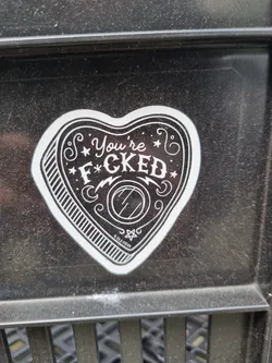 A heart-shaped planchette sticker with the text "You're F*cked" in a vintage style.