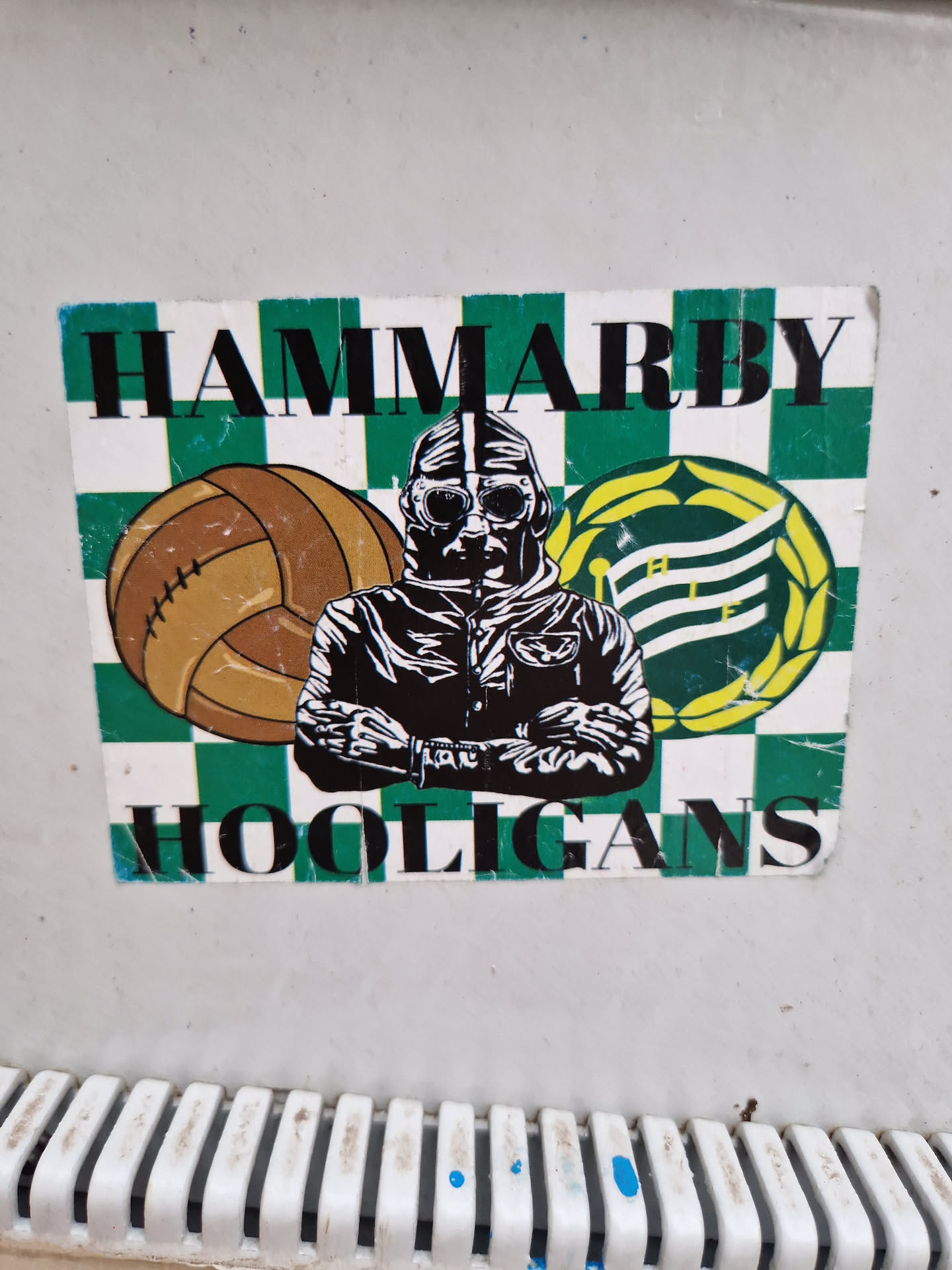 A sticker depicting a man wearing goggles and a leather jacket, a football, and a logo, all on a green and white checkered background. The text 'HAMMARBY' is at the top and 'HOOLIGANS' at the bottom.