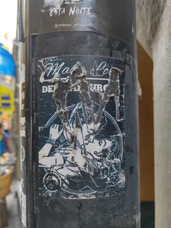 A damaged sticker featuring a black and white illustration of a couple embracing. The text on the sticker is partially obscured due to damage but appears to say "Malo" and other words that are difficult to fully decipher. The sticker shows wear and tear, with parts of the surface peeled off.