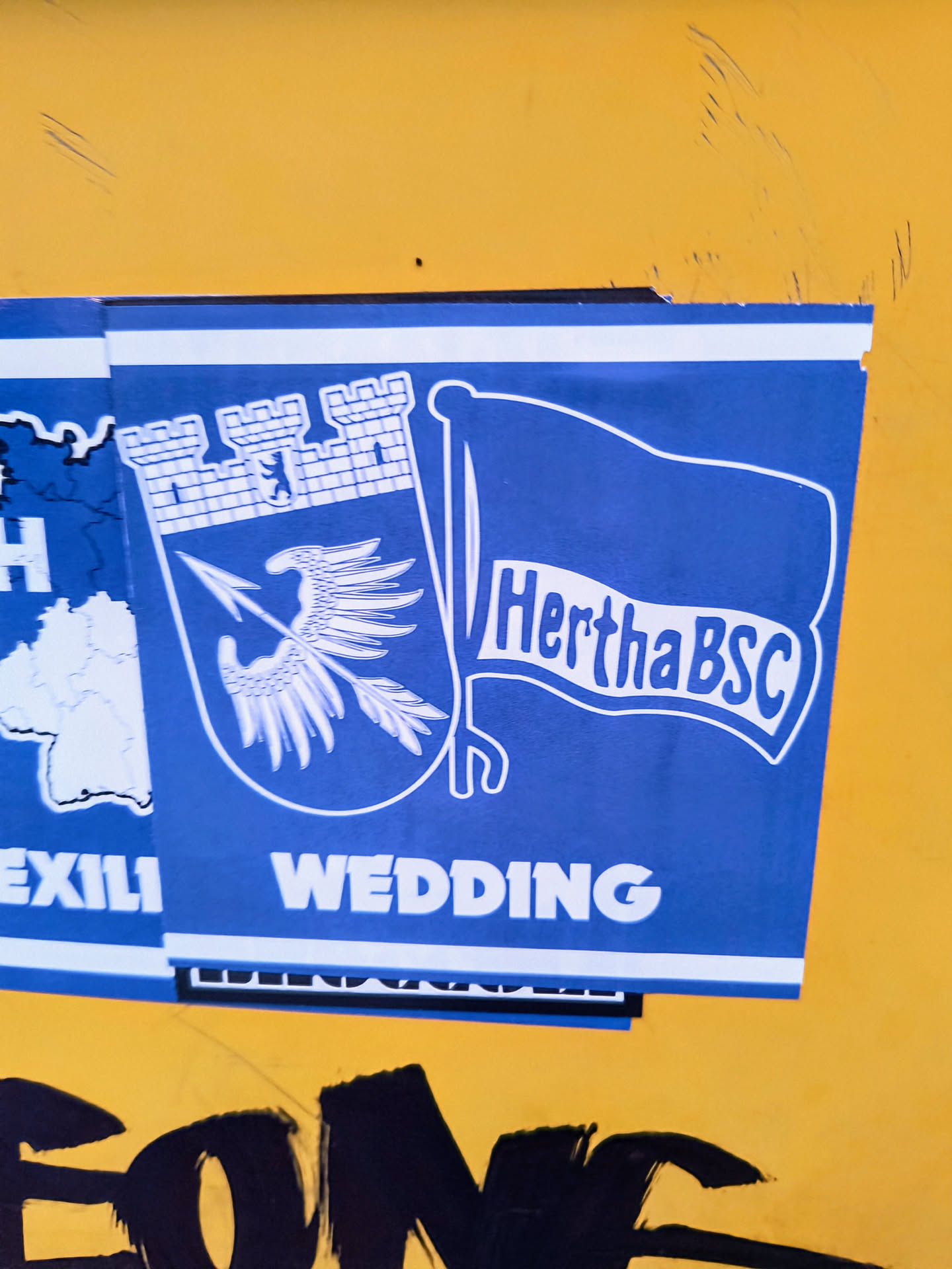 A blue and white sticker featuring the Hertha BSC logo and the word "WEDDING". The logo includes a shield with a griffin and a flag with the club's name.