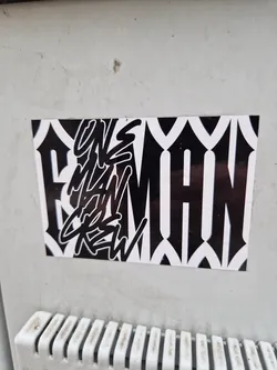 Black and white sticker with the text "Uns Man Crew" in a stylized graffiti font. The background features a geometric pattern.