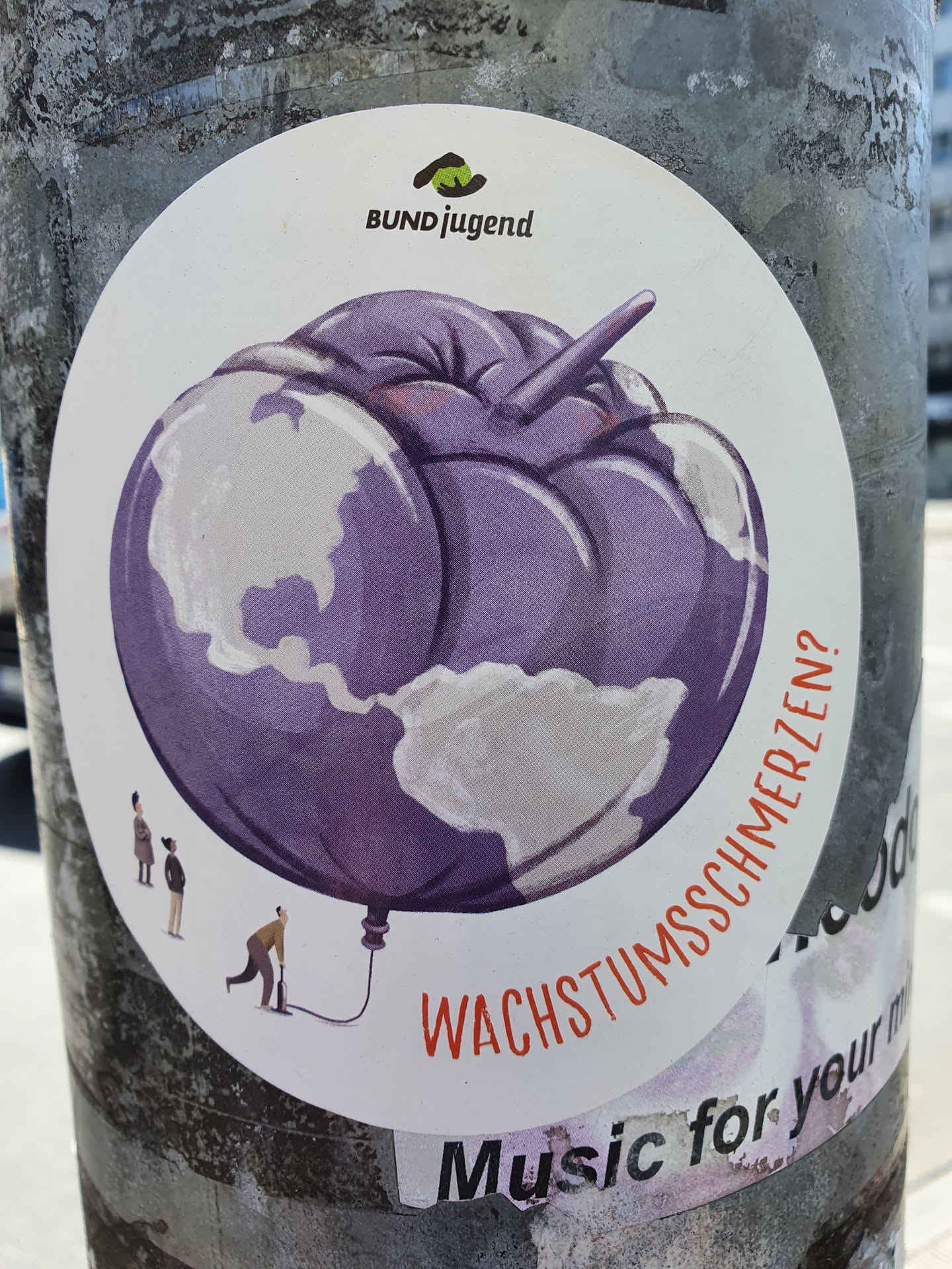 A round sticker with an illustration of the earth as a purple balloon being inflated by a small person. The text "Wachstumsschmerzen?" is visible at the bottom, which translates to "growing pains?" in English.  The sticker also features the logo of Bundjugend at the top.