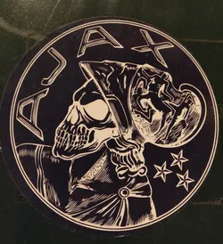 Round sticker featuring a skull wearing a helmet with the word AJAX around it. The style is reminiscent of woodblock prints, with a dark color scheme and intricate details. Three stars are visible near the skull's right shoulder.