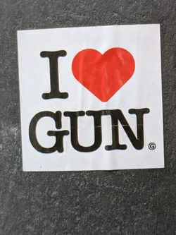 A sticker with a red heart and the text "I ♥ GUN".