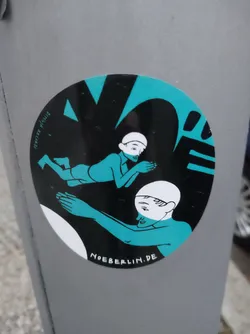 Round sticker featuring a minimalist, stylized illustration in teal and black. Two figures are depicted, one seemingly reclining and the other reaching towards them. The artwork has a bold graphic style. The text 'NOEBERLIN.DE' is visible at the bottom.