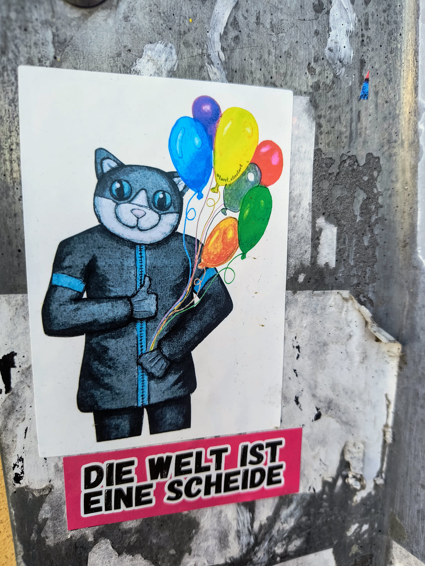 This sticker depicts an illustration of a cat dressed in a suit and holding a bunch of colorful balloons. Beneath the cat is a text in German language. The overall impression is a mix of whimsy and bold statement.