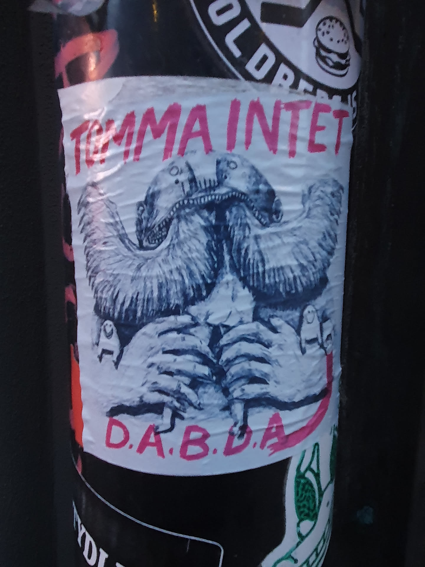 A sticker with a drawing of a two headed creature and the text "Tomma Intets" and "D.A.B.D.A"