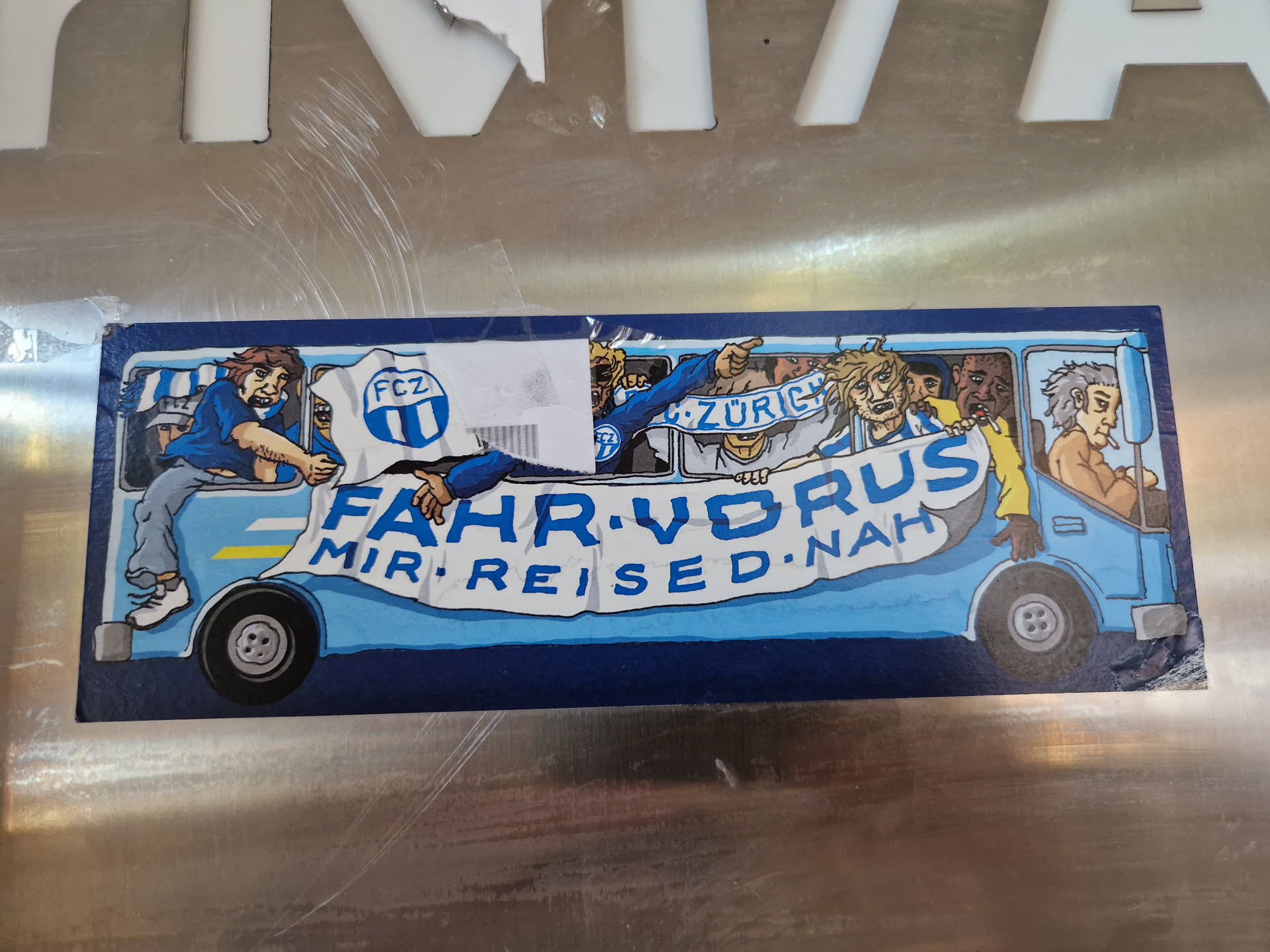 A sticker depicting a cartoon bus full of enthusiastic FCZ (FC Zürich) fans.  The text on the banner reads 'FAHR VOR RUS MIR REIS ED NAH'.