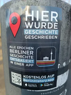 This sticker promotes the berlinHistory app, which provides location-based information about Berlin's history.  The sticker features a QR code linking to the app's download page, and logos for both Apple App Store and Google Play.