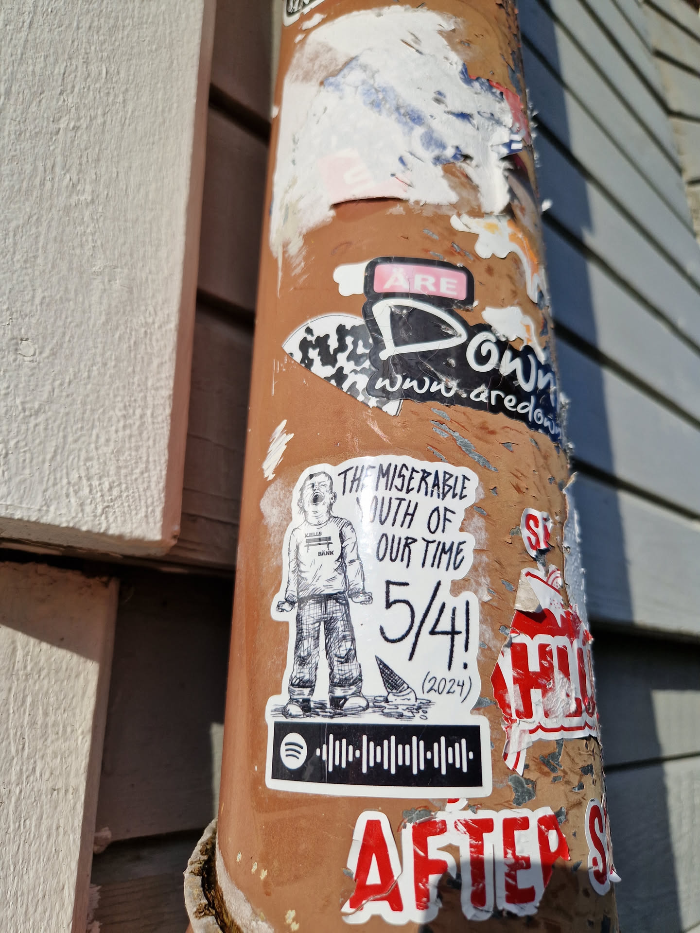 A sticker featuring a hand-drawn illustration of a person, text that reads "The Miserable Youth of Our Time" and "5/4! (2024)", and a Spotify code. The style is reminiscent of indie music or zine culture. 