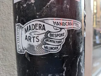 A black and white sticker featuring a hand pointing to the right with the words Madera Arts.  Other words on the sticker include Handcrafted, Bespoke, Architectural and Millwork. There is also smaller text that says Austell, Ga.