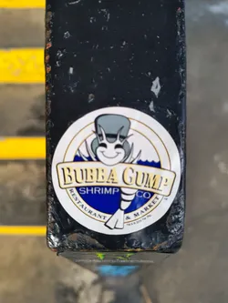 A sticker featuring the Bubba Gump Shrimp Co. logo.  The logo depicts a cartoon shrimp wearing a top hat and monocle. The text on the sticker reads "Bubba Gump Shrimp Co. Restaurant & Market."