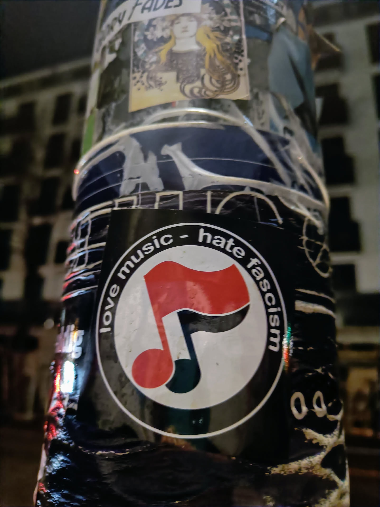 A round sticker with a musical note symbol and the text "Love music - hate fascism". The musical note is red and black, and the text is in a circle around it.