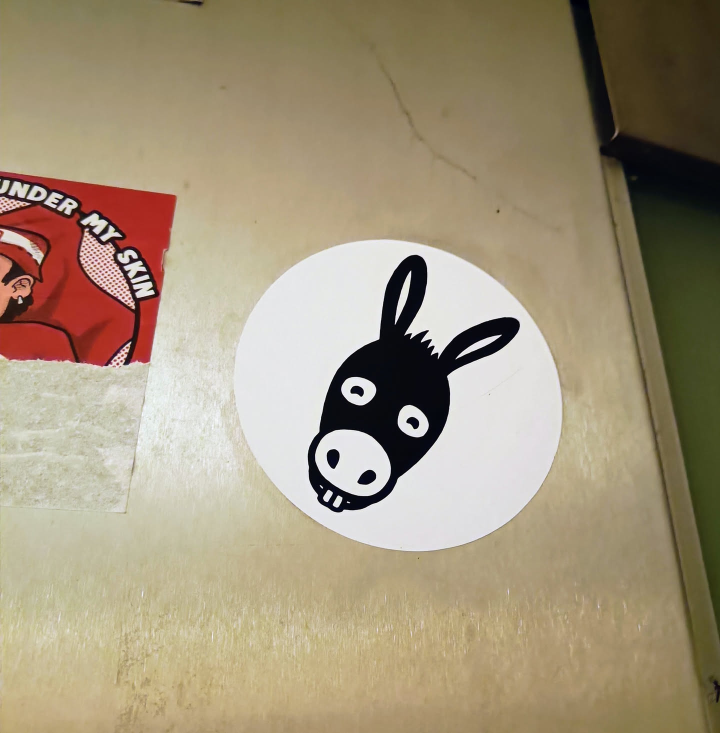 A simple sticker of a donkey's head. The donkey is black and white and has a simple design. The sticker is round and white with a black outline.