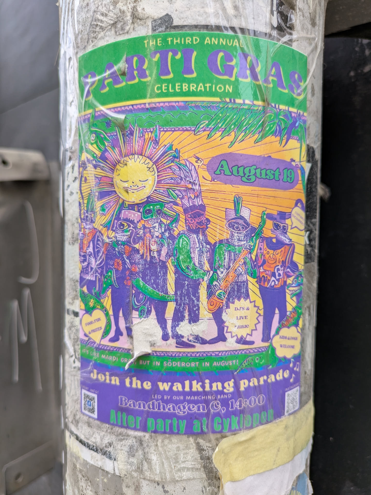 The sticker is a promotional flyer for the Third Annual Arti Gras Celebration on August 19. It features a band in colorful costumes.