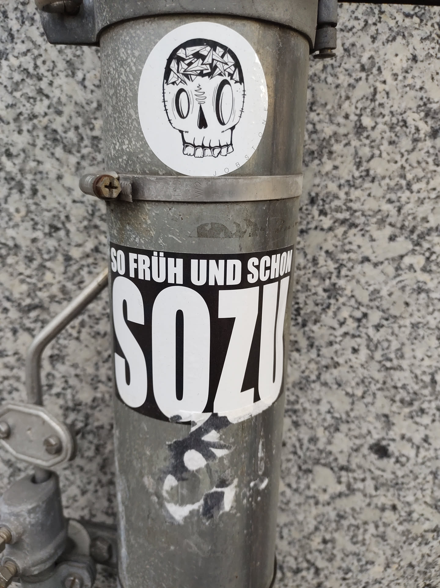 A sticker featuring a skull with its head filled with small objects. Below is another sticker that says SOZU, with the phrase "So früh und schon" written above it.