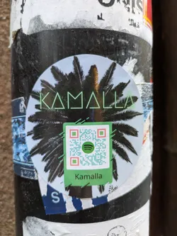 Round sticker featuring the text "Kamalla" in a stylized font, overlaid on an image of a palm tree. A QR code linking to Spotify is also present. 