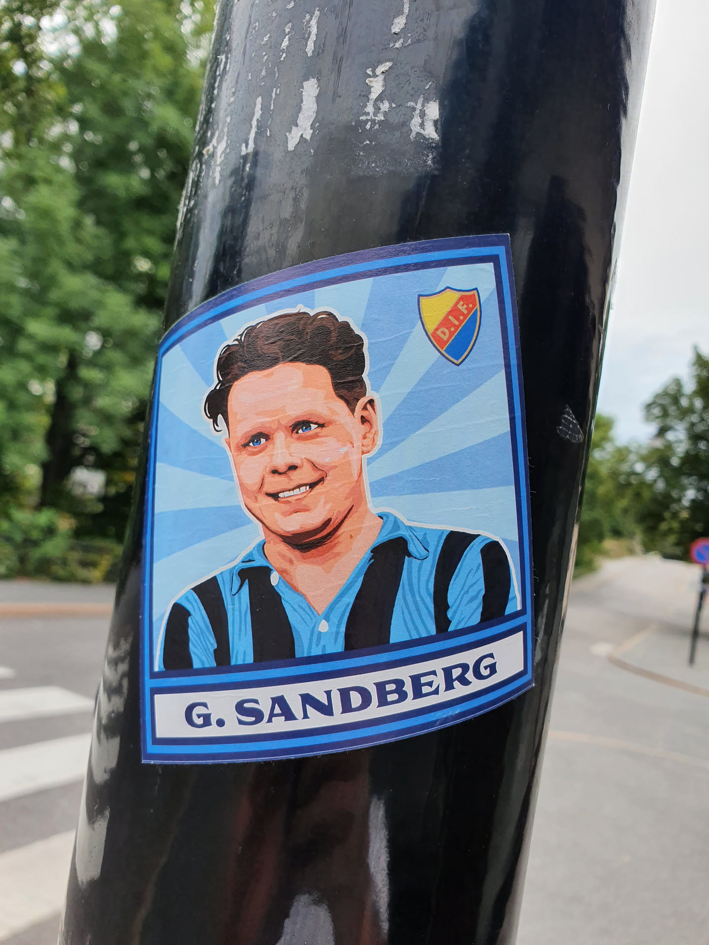 A sticker featuring a portrait of G. Sandberg, possibly a football player, with a team logo (D.I.F.) in the background. The style is reminiscent of vintage sports cards.