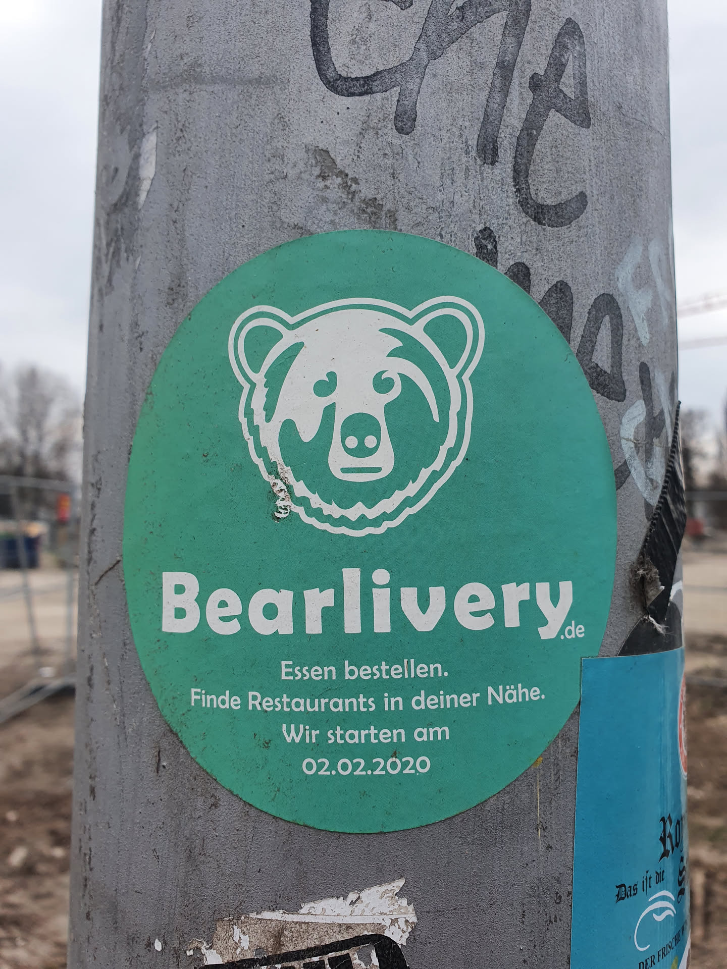A teal circular sticker featuring a white bear illustration and the text "Bearlivery.de". Below the logo, it reads: "Essen bestellen. Finde Restaurants in deiner Nähe. Wir starten am 02.02.2020."  which translates to: "Order food. Find restaurants near you. We start on 02.02.2020."