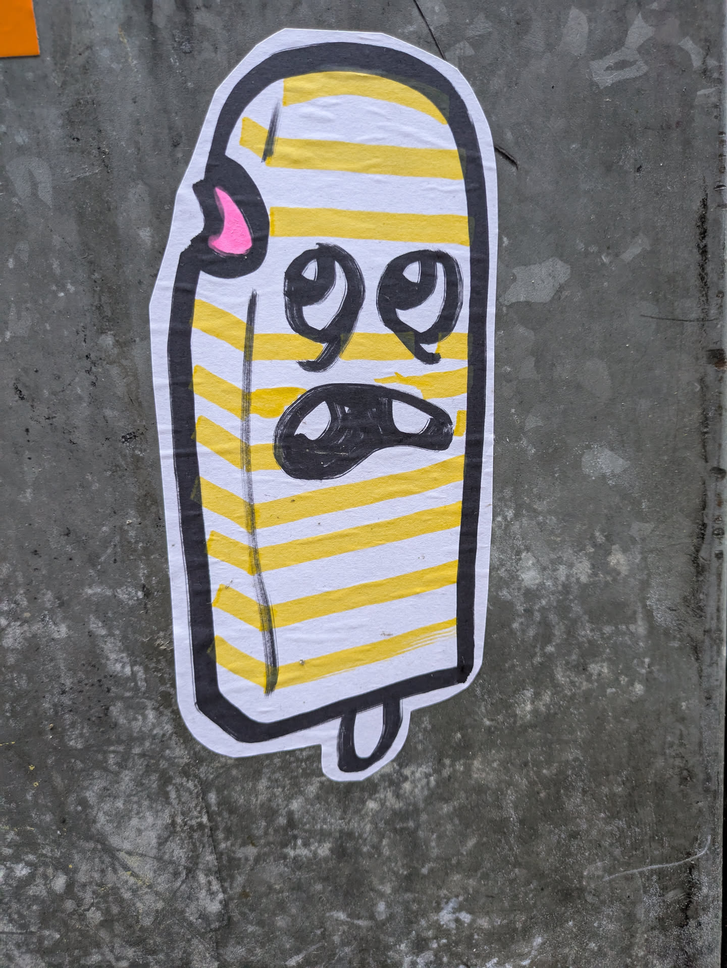 This sticker features a whimsical illustration of a popsicle with yellow and white stripes. The popsicle has a cartoonish face with big eyes and a slightly frowning mouth. It has a small pink detail near the top. The style is simple and playful.