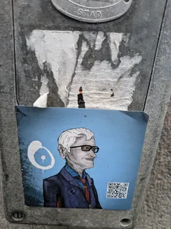 This sticker is an illustration of a man, possibly a portrait, rendered in a somewhat cartoonish style with visible brushstrokes. He is wearing glasses and a suit and tie. The background is a solid light blue.  A QR code is included, potentially linking to more information about the subject or artist.  The sticker itself seems to be hand-drawn and/or digitally printed.