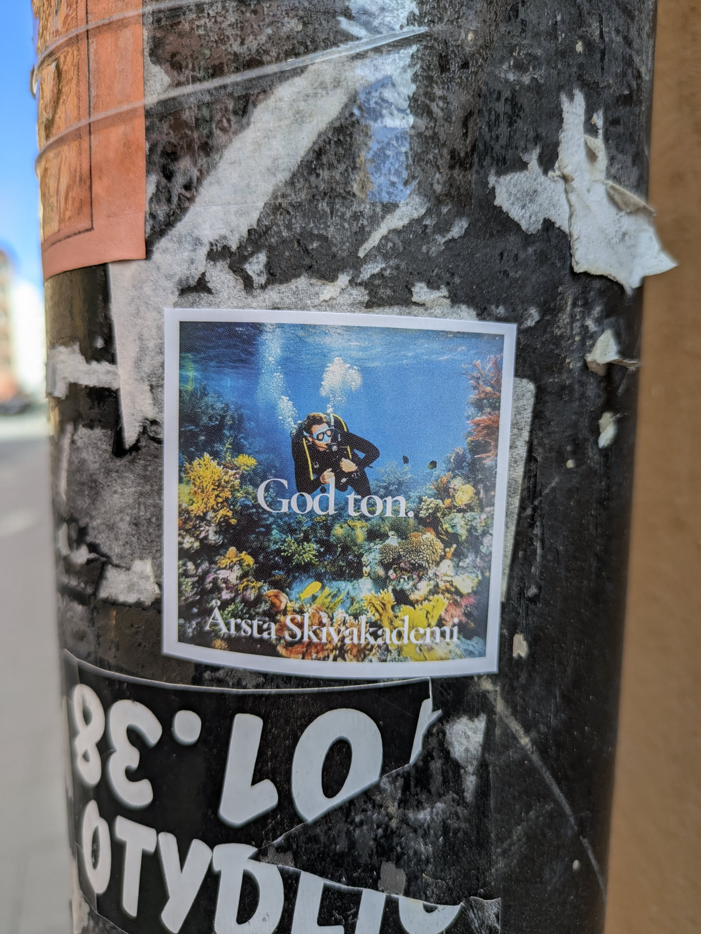 This sticker features a diver surrounded by colorful coral reefs. Above the diver, it says "God ton" and below the image is written "Arsta Skivakademi".