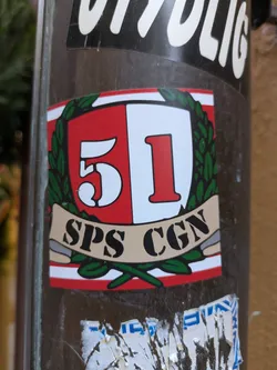 A sticker featuring a shield-like emblem with the number 51, the letters SPS, and the letters CGN.  The emblem is surrounded by green laurel leaves and is set against a red and white background. 