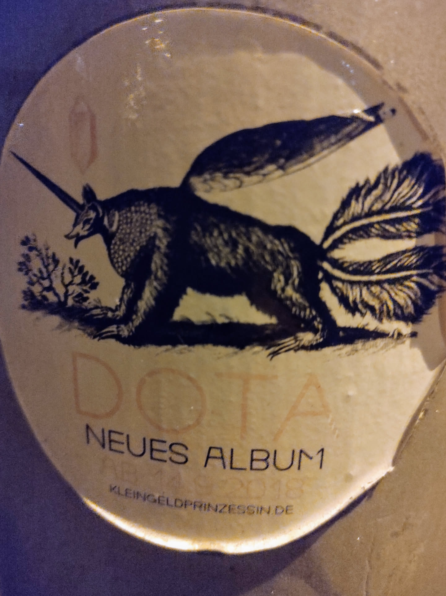 Round sticker featuring a fantastical creature, a mix between an anteater and a unicorn, with wings and a long tail. The text on the sticker says "DOTA NEUES ALBUM" and "KLEINGELOPRINZESSIN.DE".