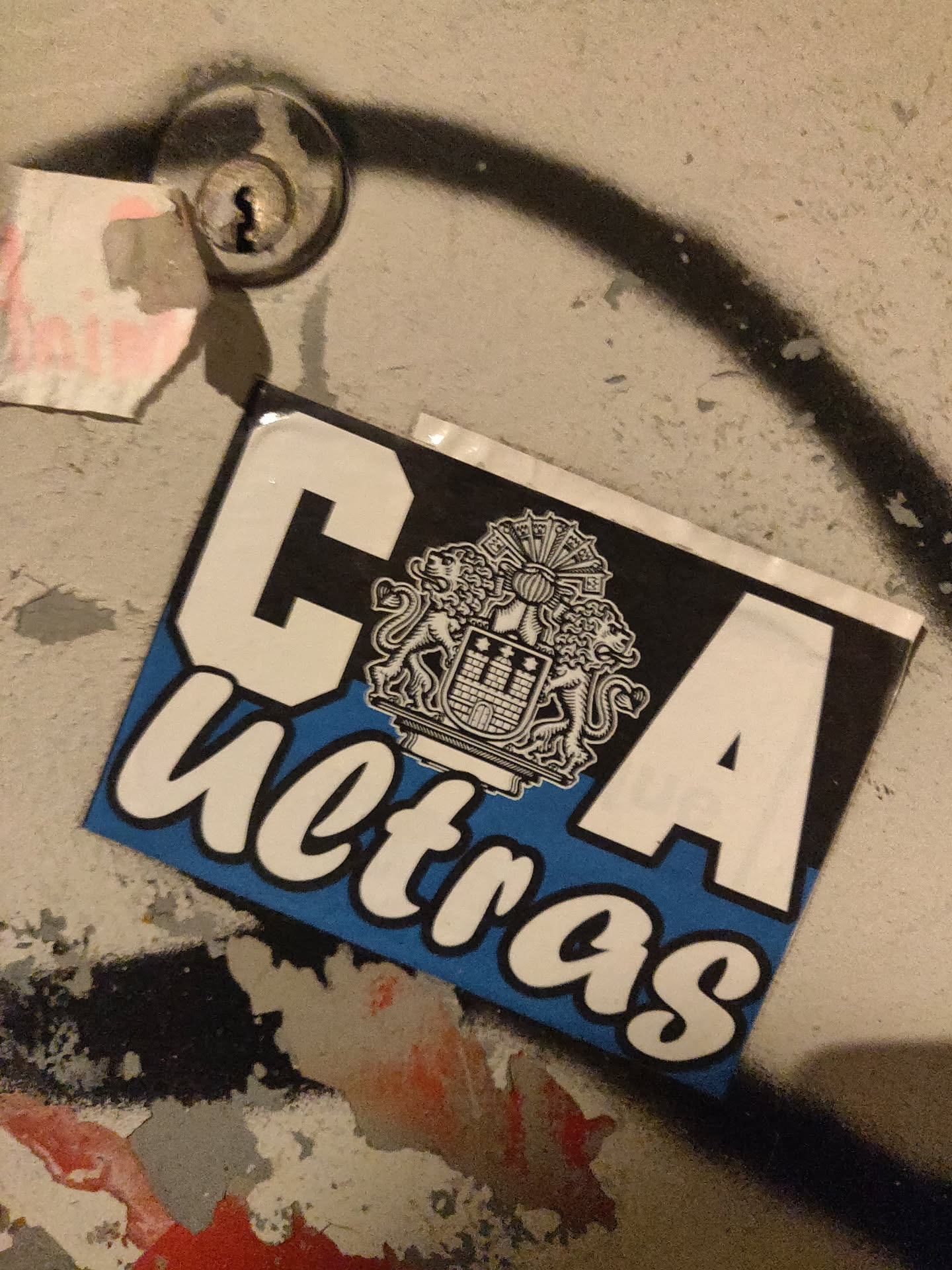 A sticker featuring the letters CA and the word "ultras" in a stylized font. A crest is prominently displayed above the text. The sticker is affixed to a weathered surface. 