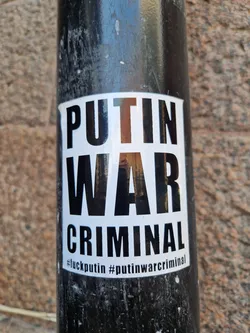 A sticker expressing anti-war sentiment against Vladimir Putin.  The sticker has bold black text on a white background.