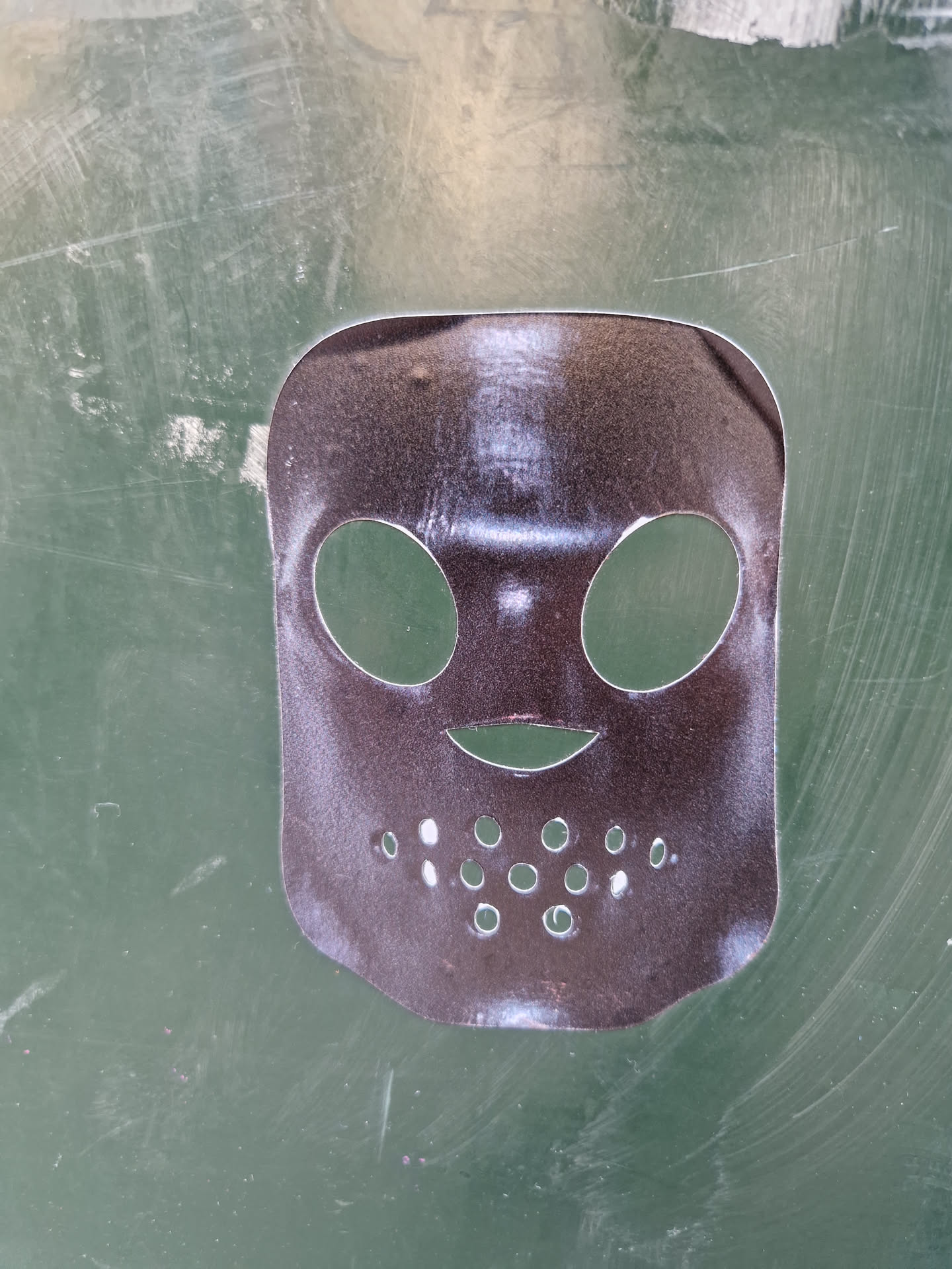 This sticker features a dark-colored hockey mask with cut-out eye and mouth holes.  It's a simple design, perfect for adding a touch of spooky fun to any surface.