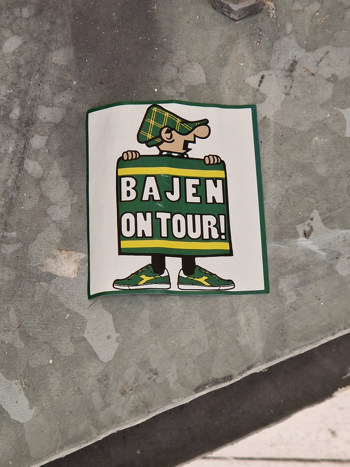 A sticker featuring a cartoon character holding a sign that says "Bajen On Tour!"