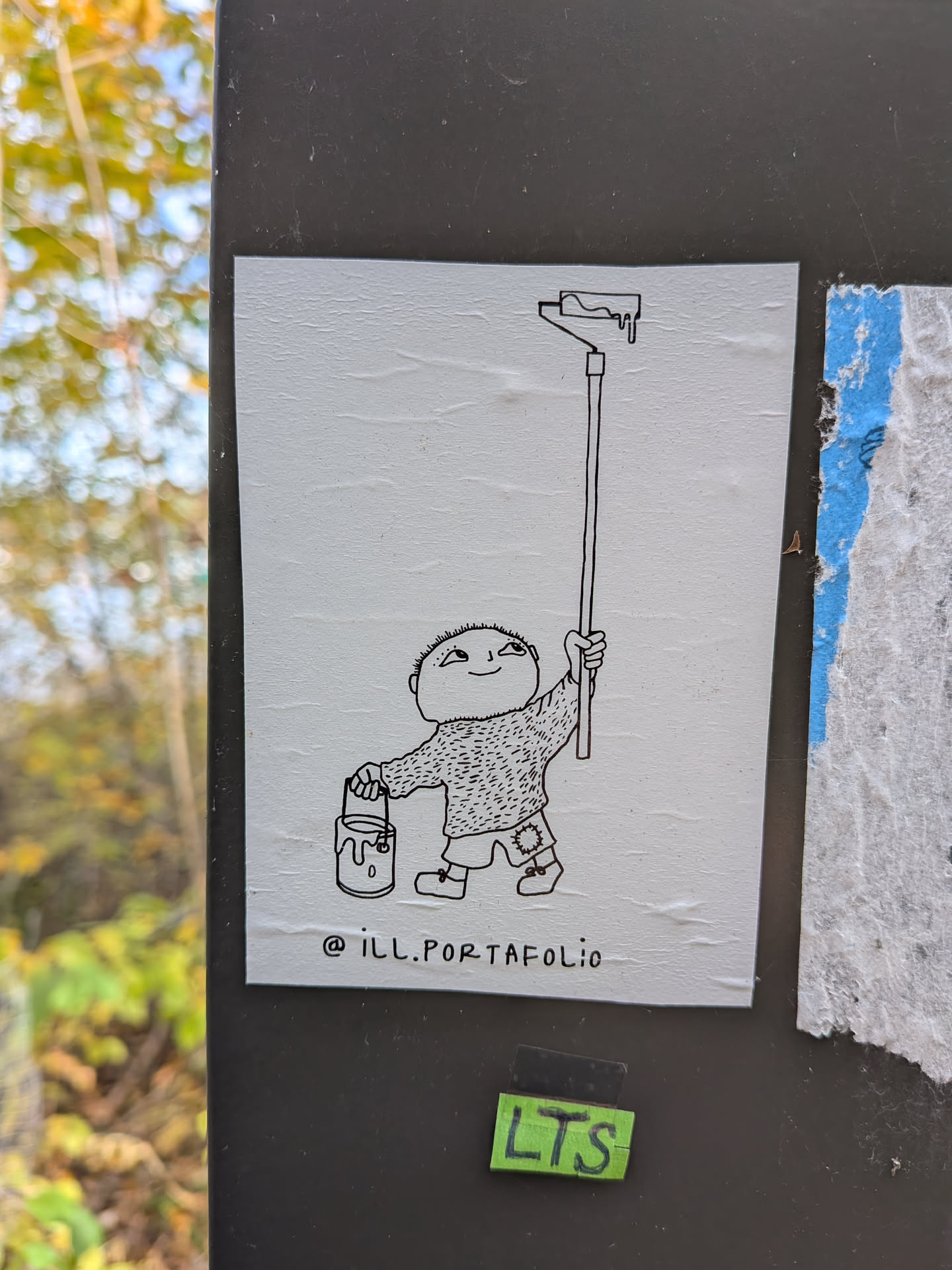 The sticker features a simple, hand-drawn black and white illustration on a textured white background. In the center, a small, round-headed character with a wide smile and a slightly mischievous expression holds a paint bucket in its left hand and a long paint roller in its right. The paint roller has a dripping effect at the top, suggesting it's loaded with paint. The character wears a fuzzy sweater and shorts with a patch on one knee. Below the illustration, the text '@ill.PORTAFOLIO' is written in a simple, lowercase font.