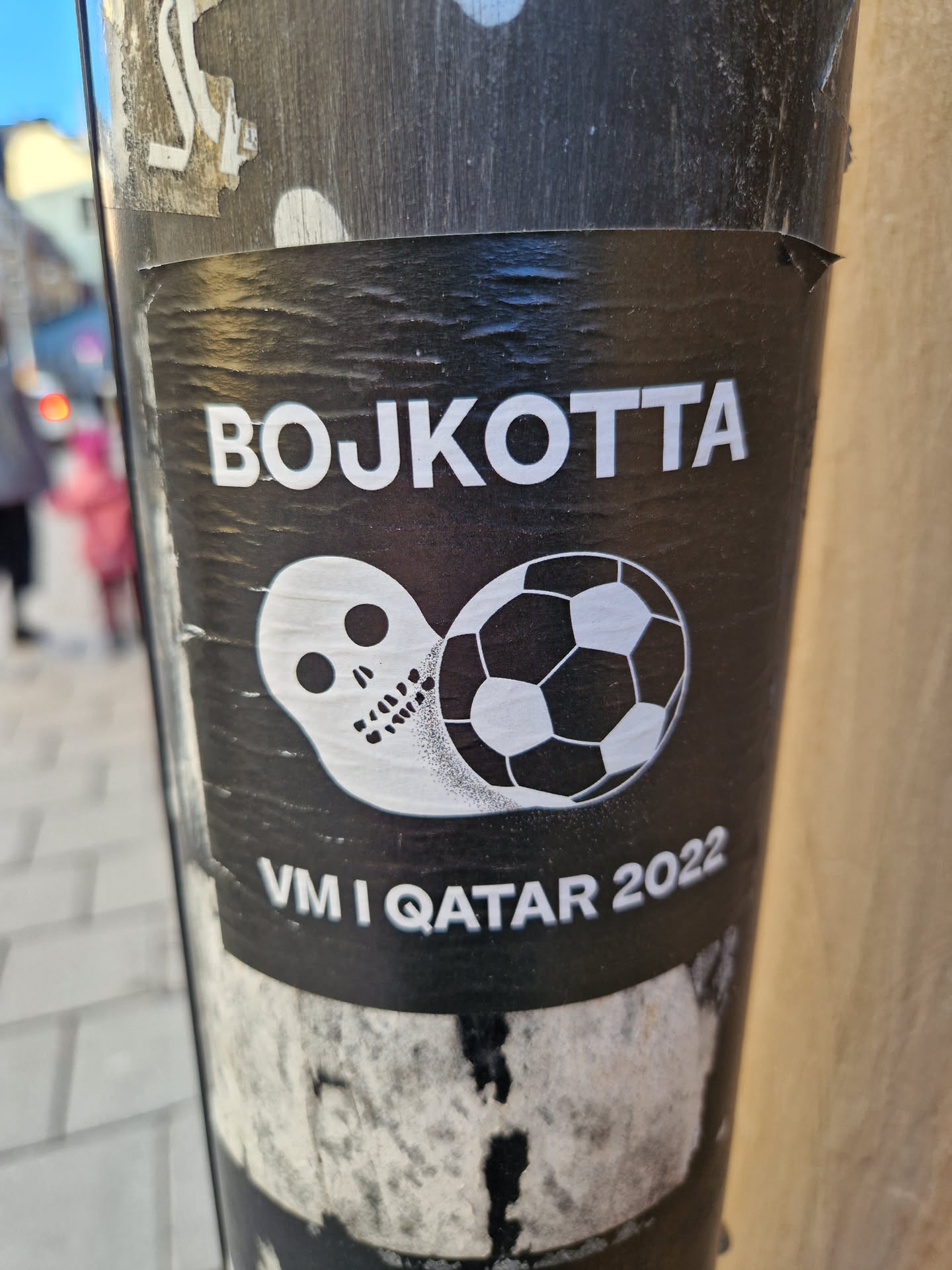 A black and white sticker with a skull and a soccer ball. The text says "BOJKOTTA" and "VM I QATAR 2022".