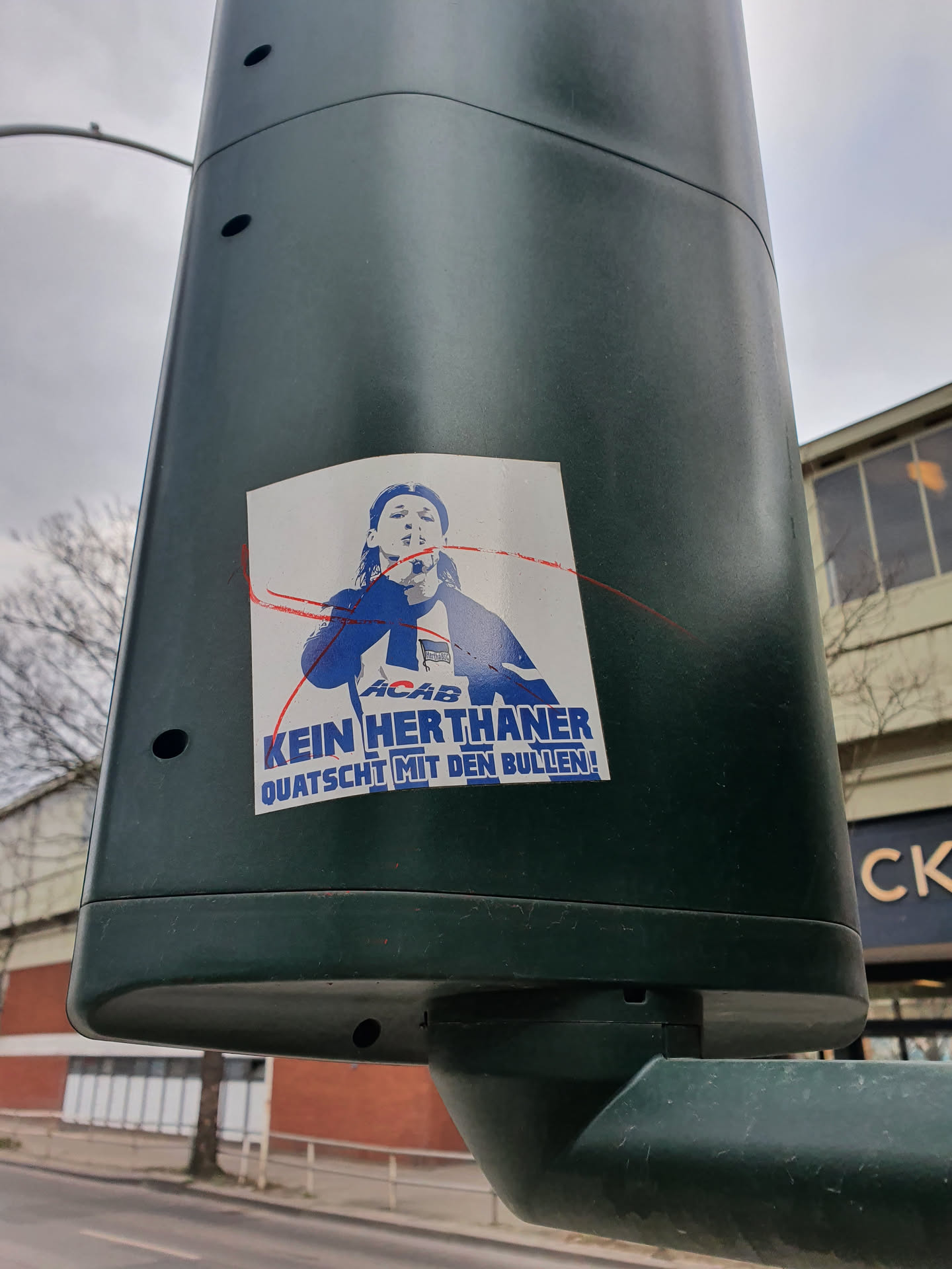 A sticker featuring a stylized image of a person, possibly a protest image, with text overlay in German.  The text translates roughly to "No Hertha fan chats with the cops!"