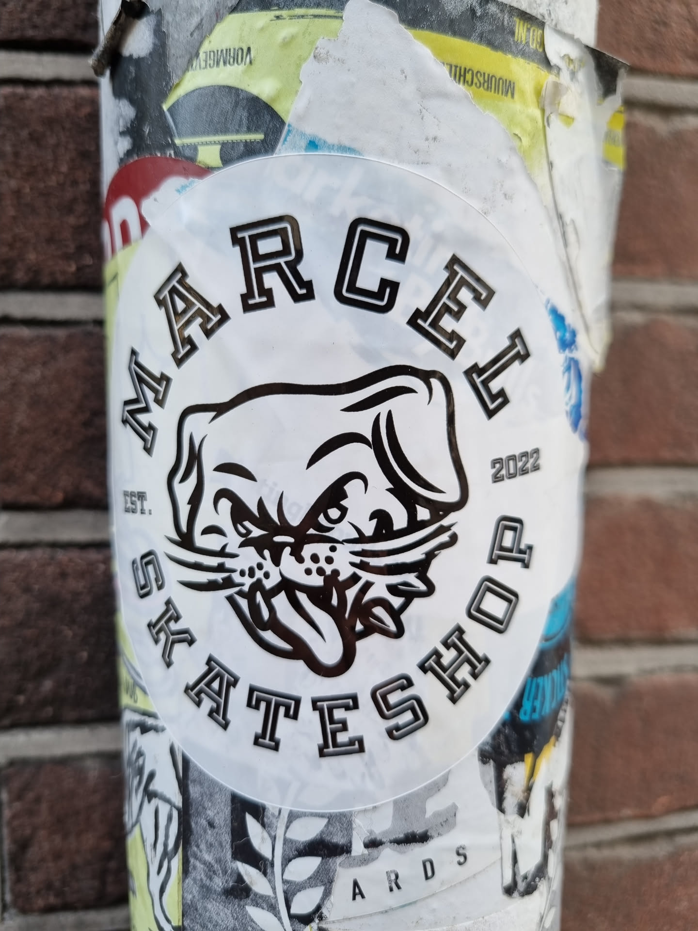 A round sticker with a black and white illustration of a dog's head and the text "MARCEL SKATESHOP" around it. The year 2022 is printed on the right side of the circle. 