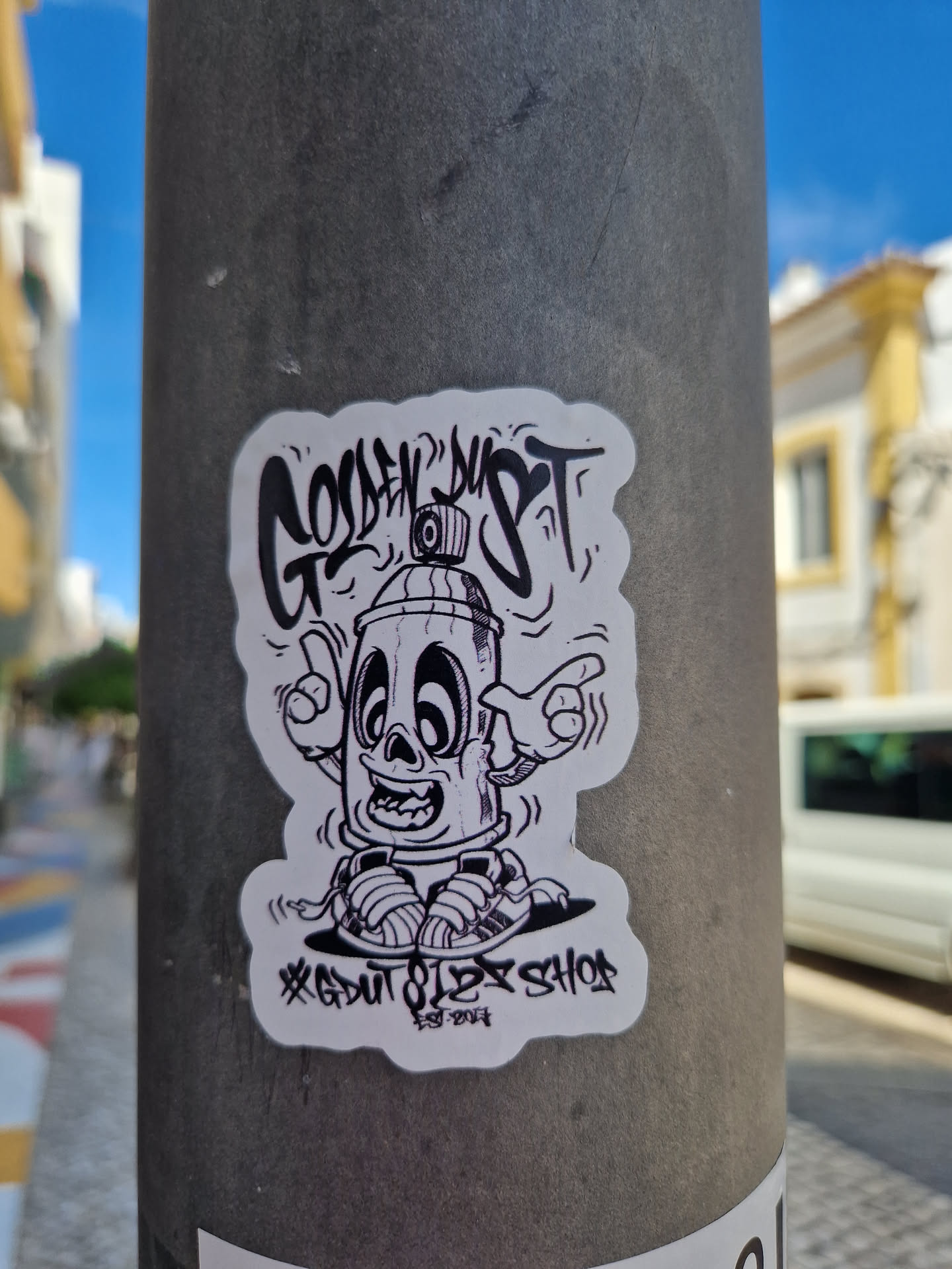 Black and white sticker featuring a cartoon spray can character with shoes. The text on the sticker says "Golden Dust" and "GDU7 OLEX SHOE 2023".
