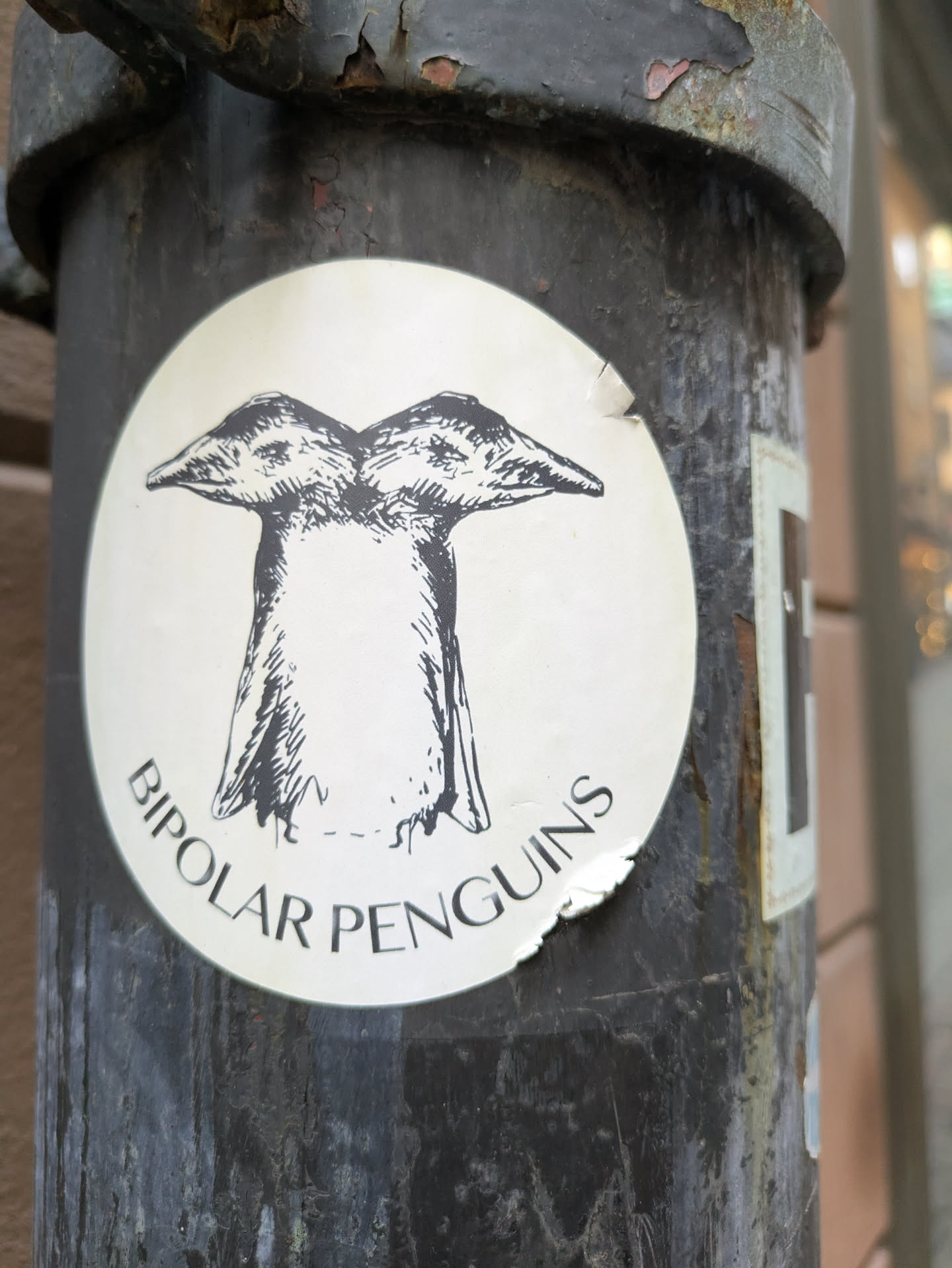 A round sticker featuring a drawing of two penguins joined together at the body, with the text 'Bipolar Penguins' written below the drawing.
