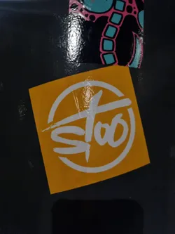 A square yellow sticker with a round logo in white. The logo features a stylized text that looks like 'Stoo'.