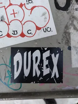 A black and white Durex sticker with the brand name in a stylized font.  The sticker shows some signs of wear and tear.