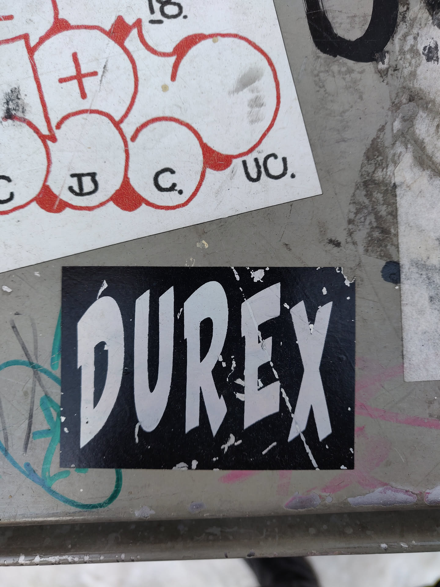 A black and white Durex sticker with the brand name in a stylized font.  The sticker shows some signs of wear and tear.