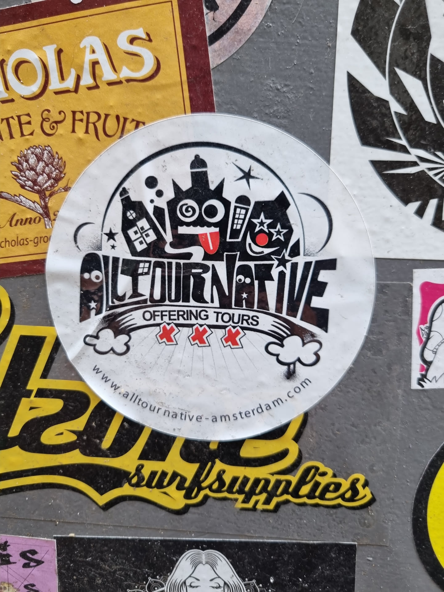 Round sticker with black and white illustration of a monster and buildings.  The text 'Alltournative' and 'Offering Tours' is present, along with a website address.