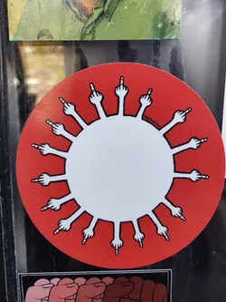 Round sticker featuring a stylized virus with each spike being a middle finger.  The background is red and the virus is white.  A small signature is visible in the center, it seems to say "2424MA".